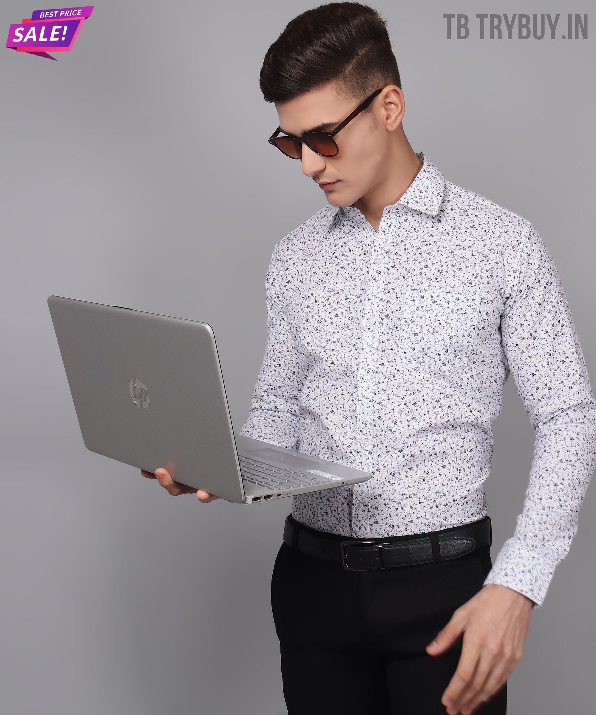 a man in a dress shirt and sunglasses using a laptop