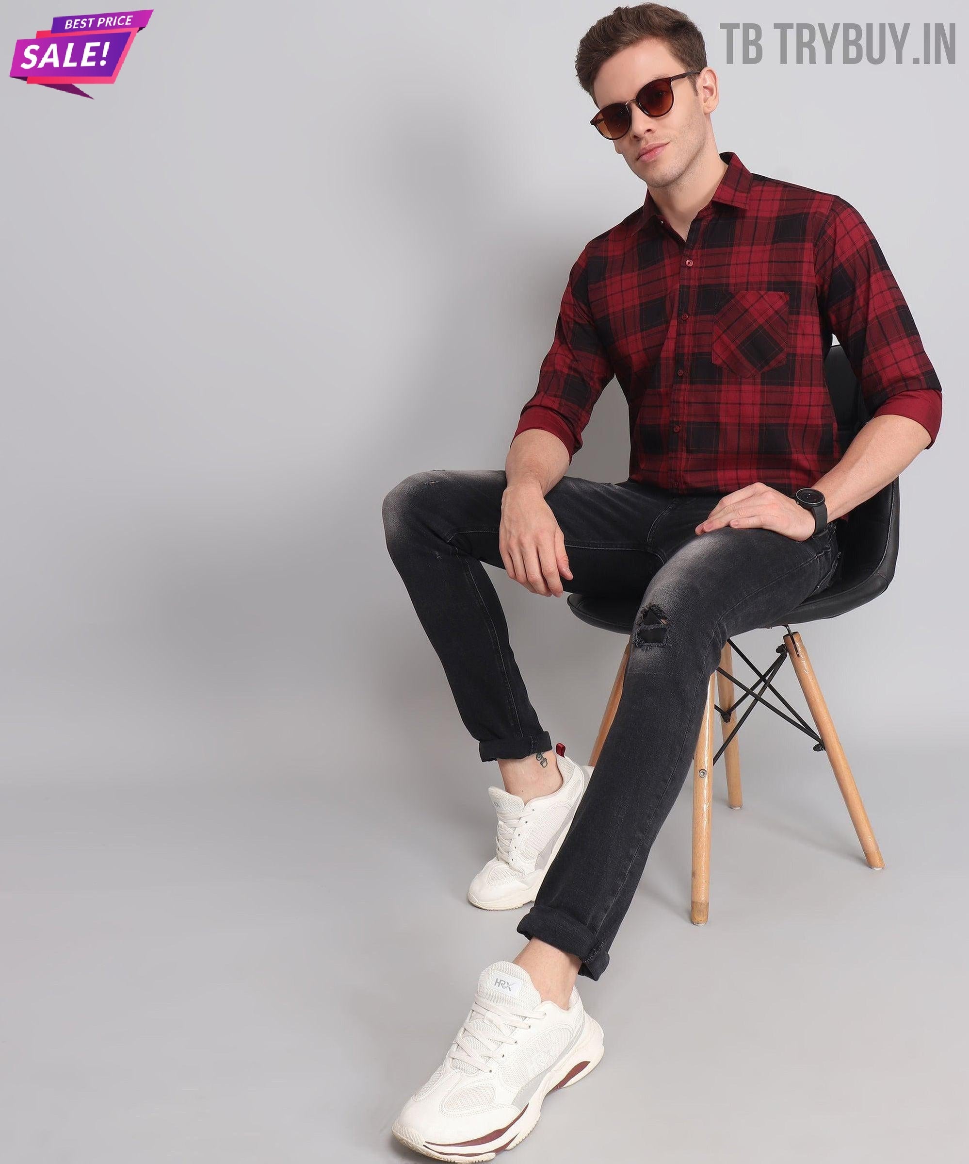 a man sitting on a chair wearing a red and black plaid shirt