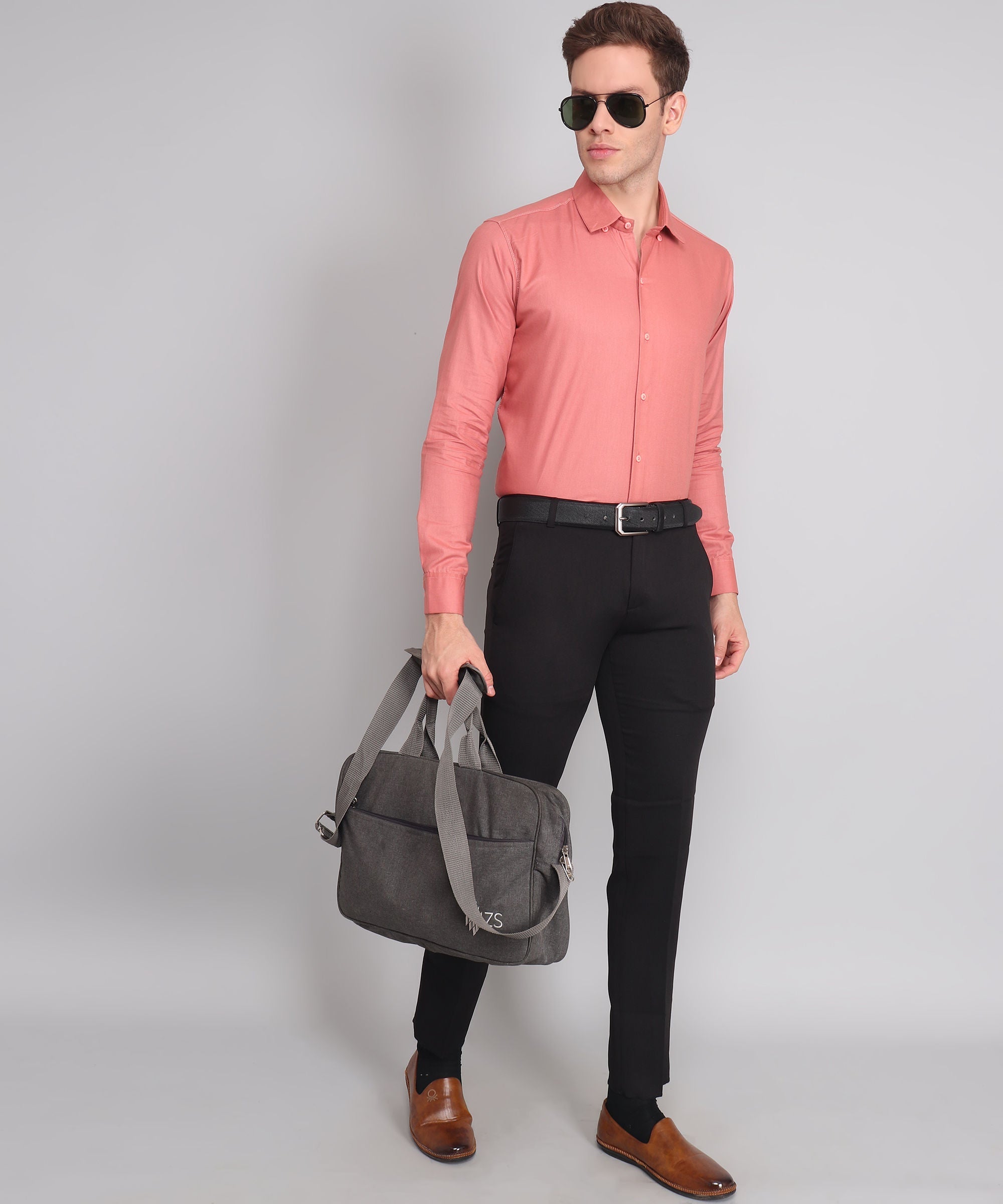 a man in a pink shirt is holding a gray bag