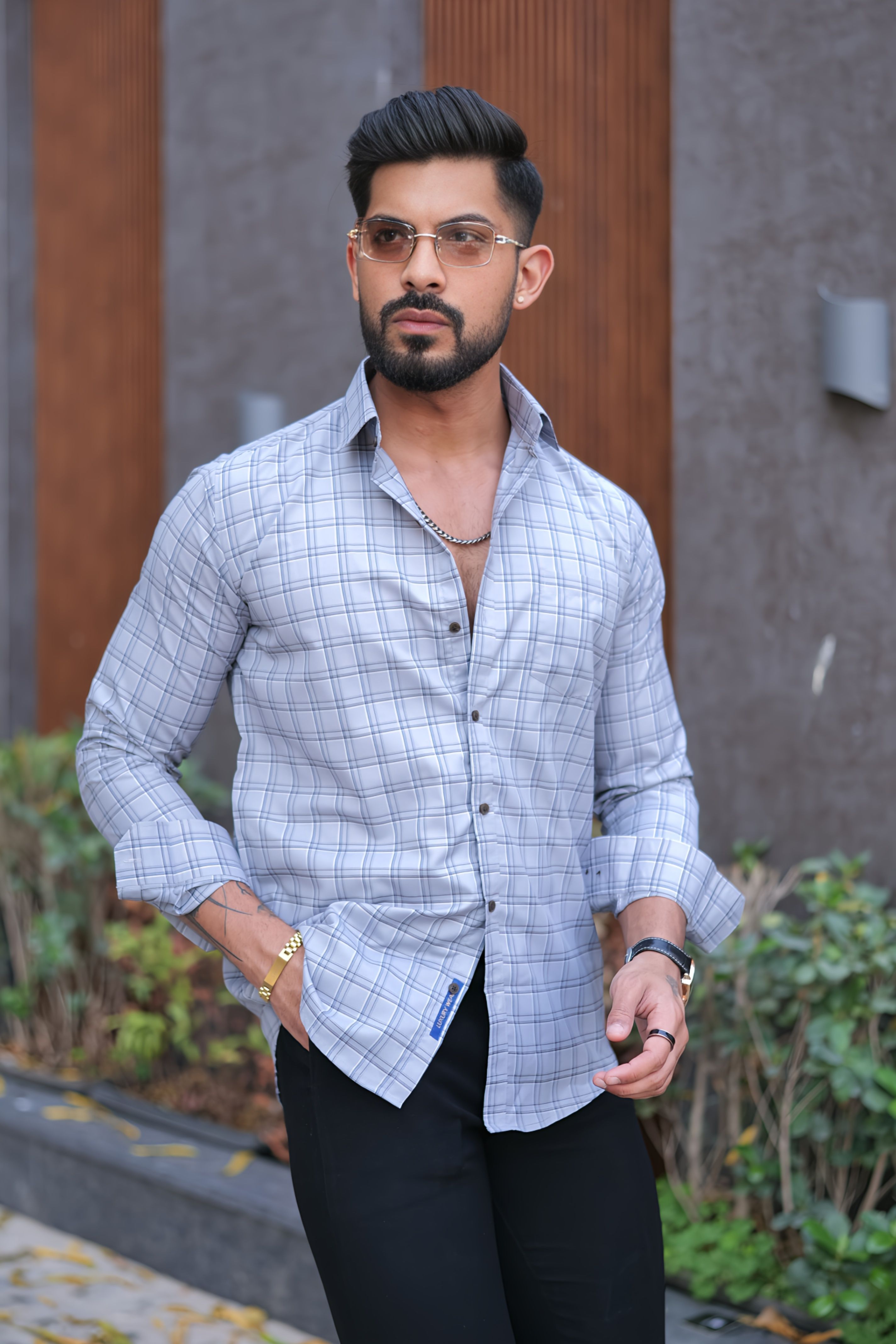 a man with a beard and glasses standing in front of a building