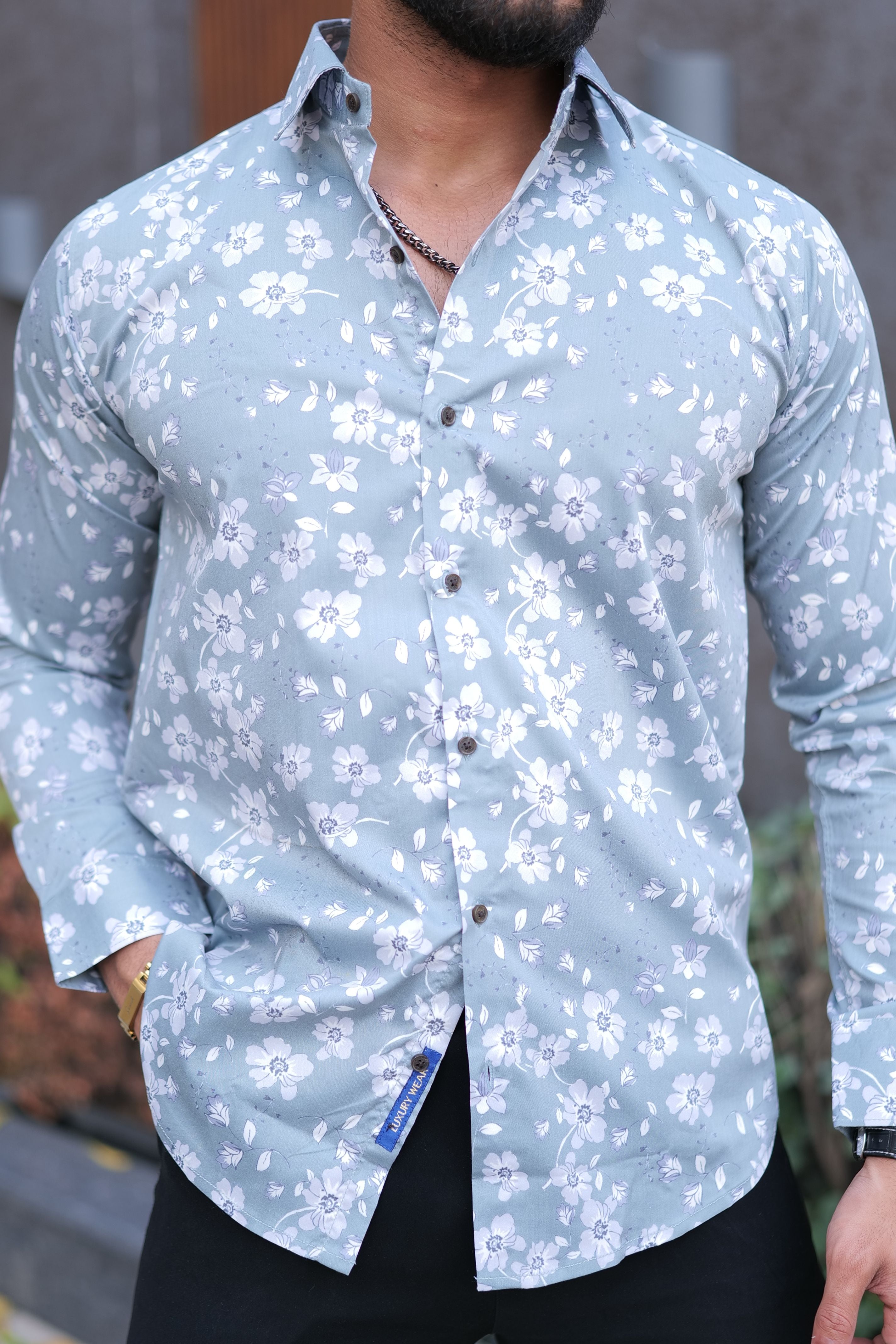 a man wearing a blue shirt with white flowers on it