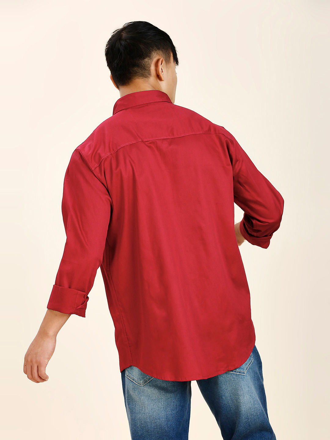 a man wearing a red shirt and jeans