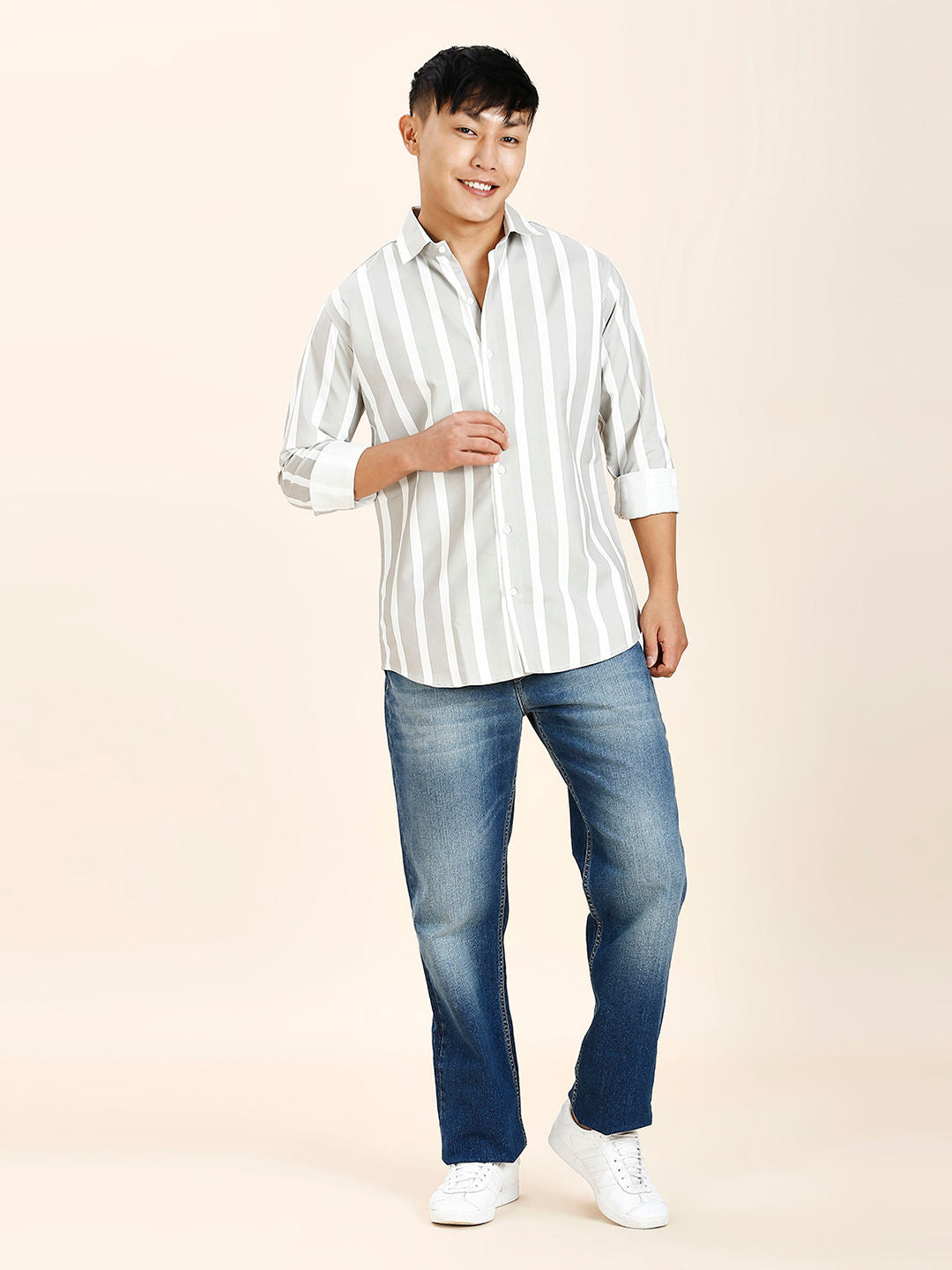 a man in a striped shirt and jeans poses for a picture