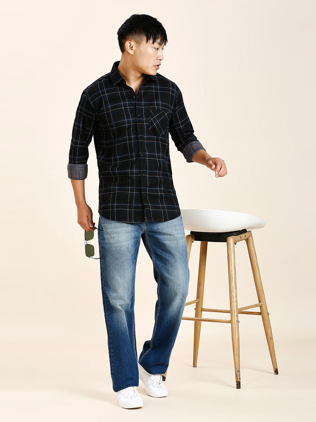 a man standing next to a stool holding a bottle