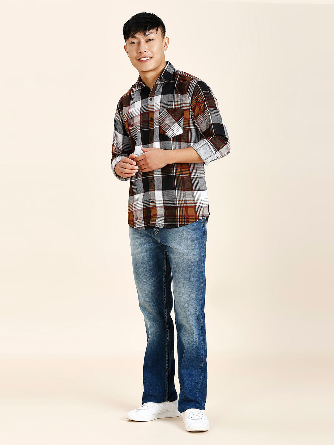 a man in a plaid shirt and jeans posing for a picture