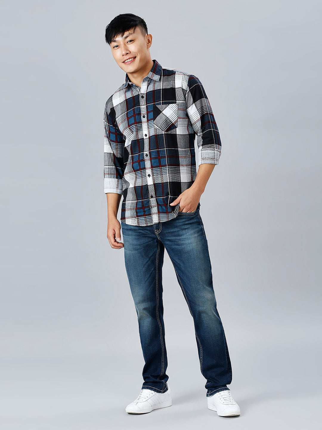 a man in a plaid shirt and jeans posing for a picture