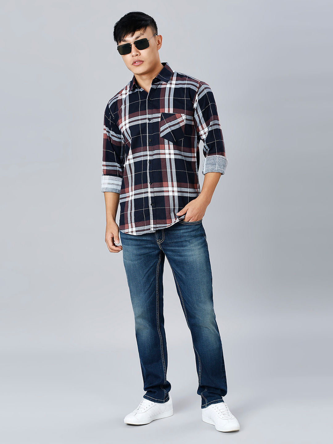 a young man wearing a plaid shirt and jeans