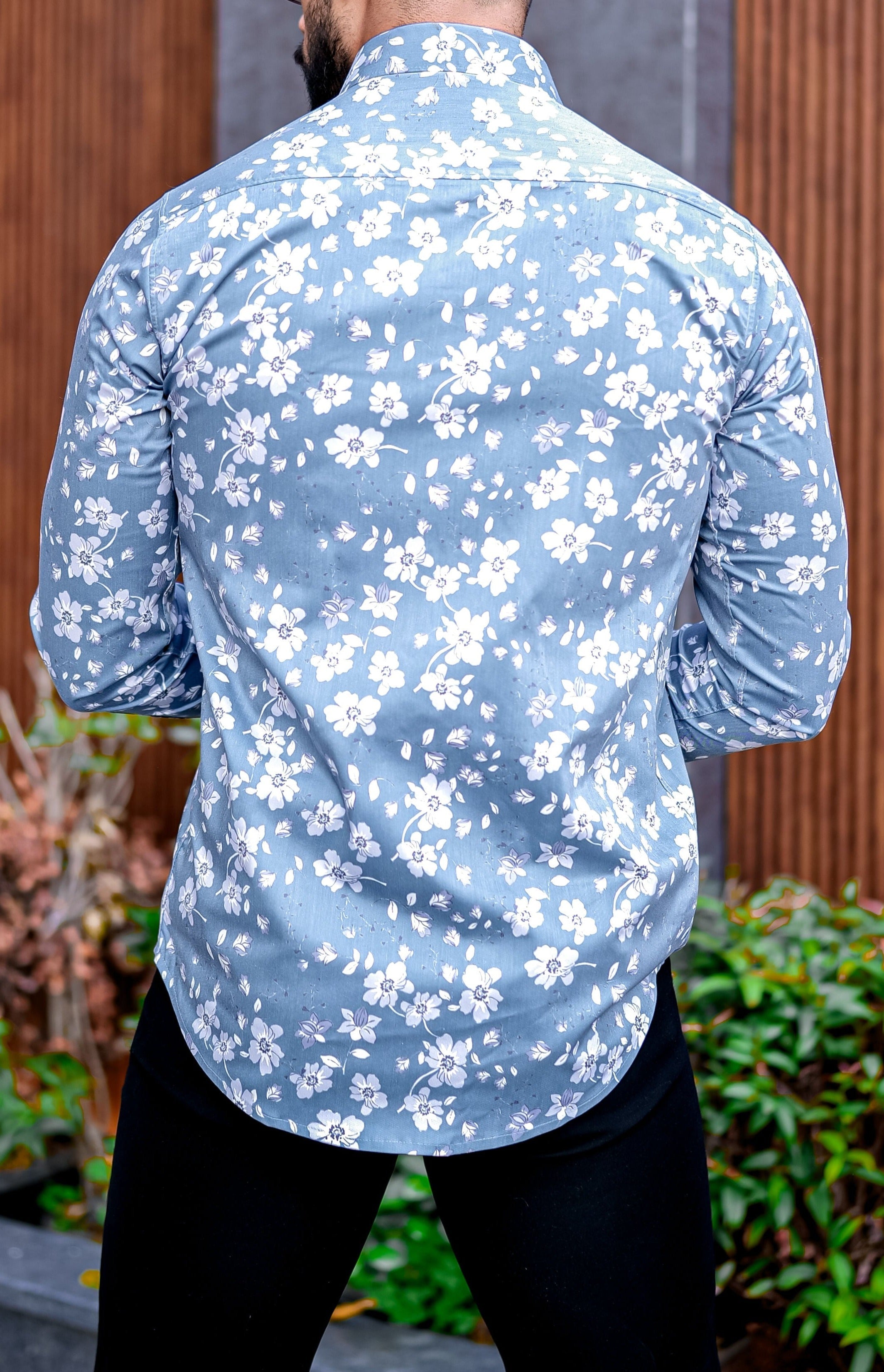 a man wearing a blue shirt with white flowers on it