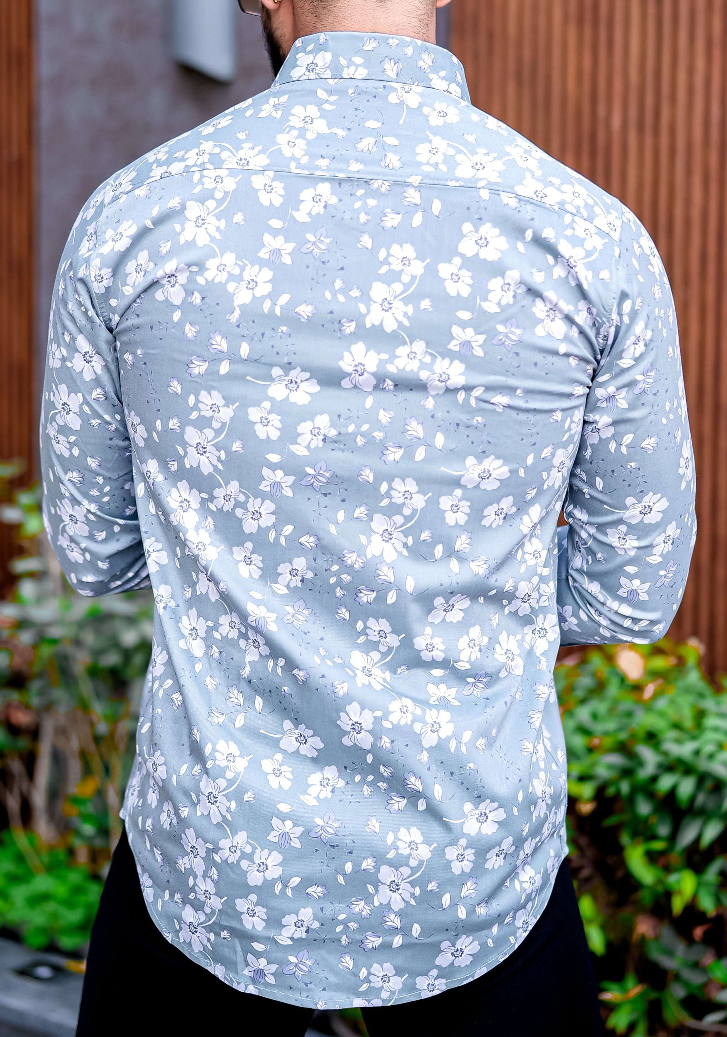 a man wearing a blue shirt with white flowers on it