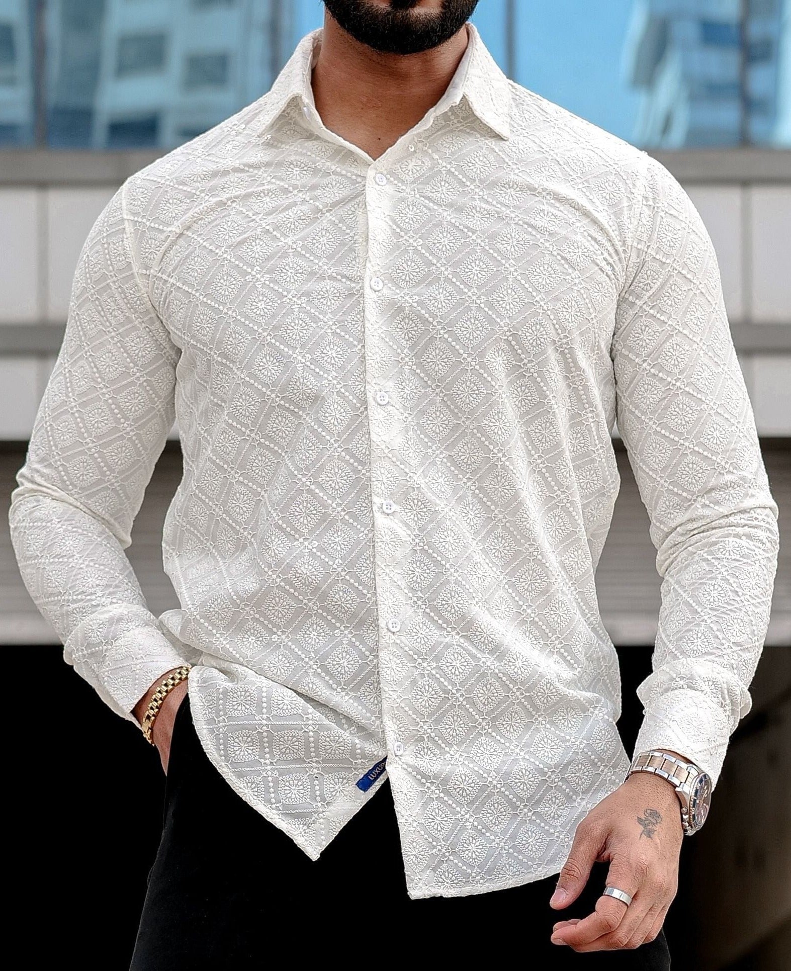 a man wearing a cream shirt and black pants