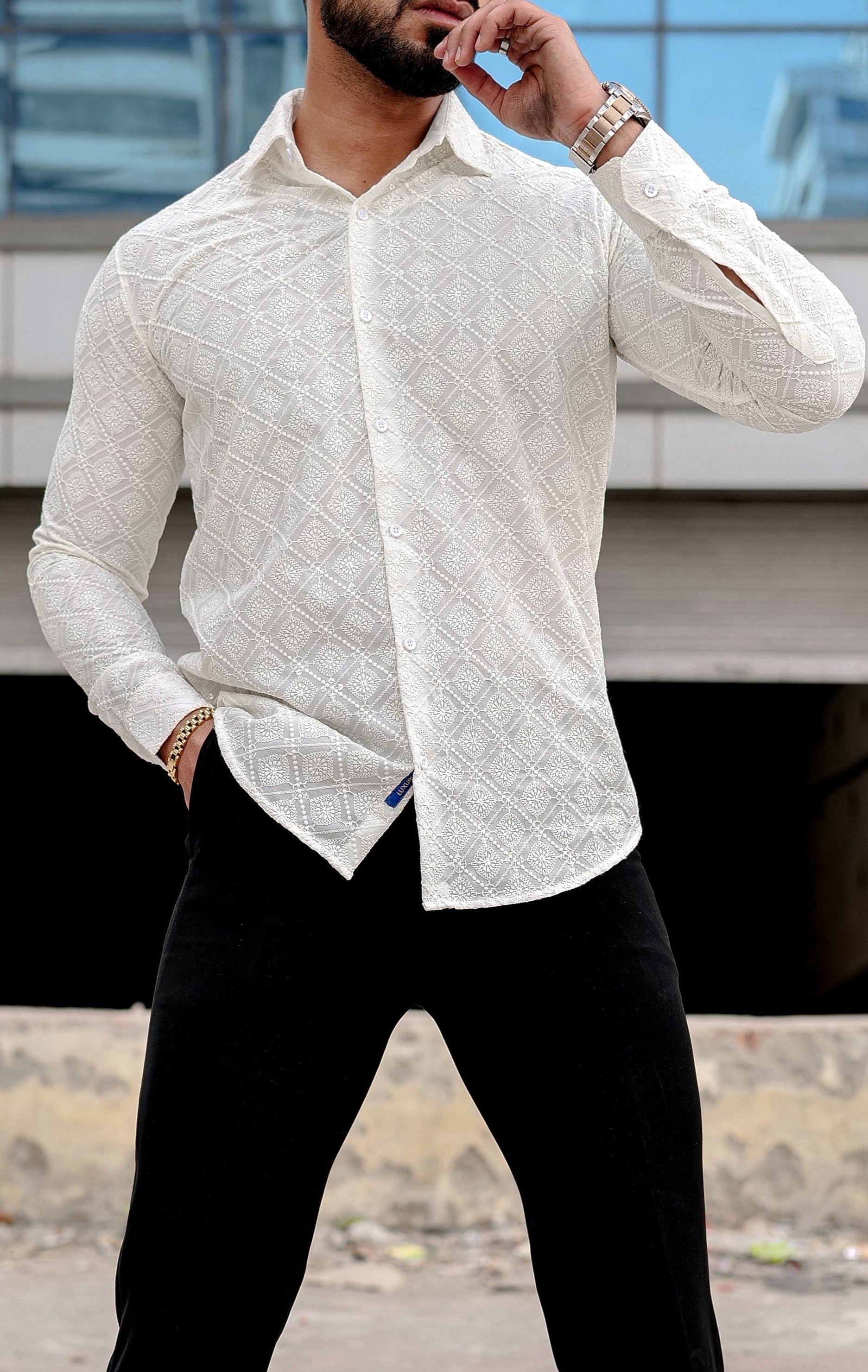 a man wearing a cream shirt and black pants