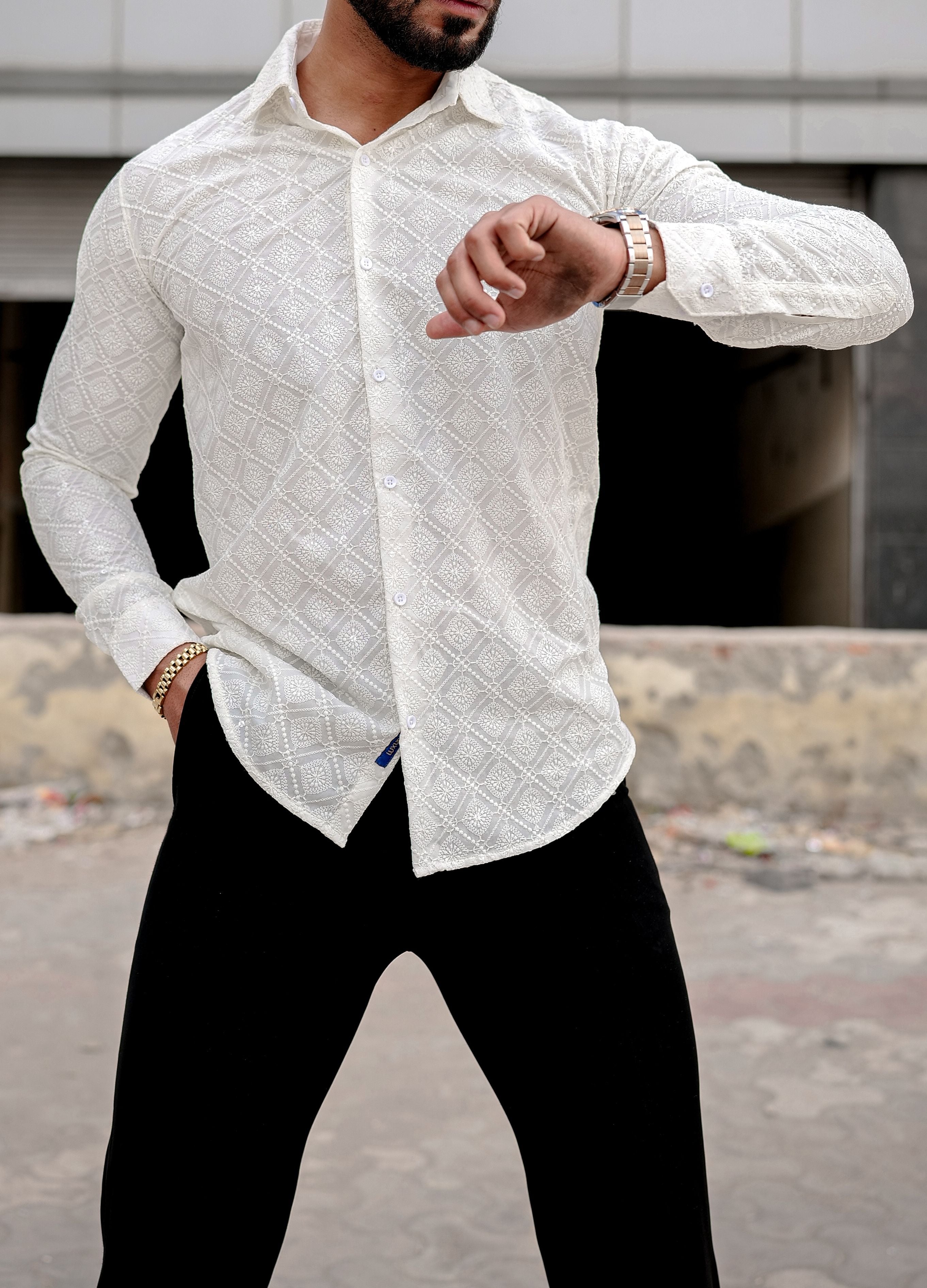 a man wearing a cream shirt and black pants