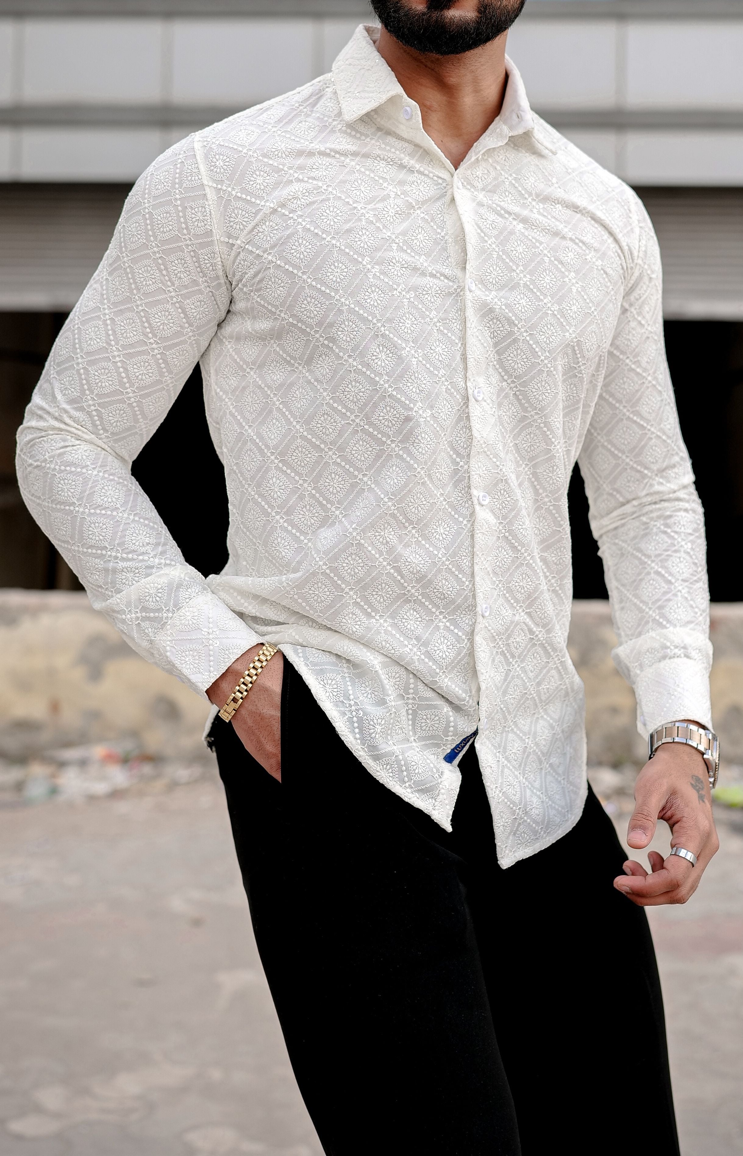 a man wearing a cream shirt and black pants