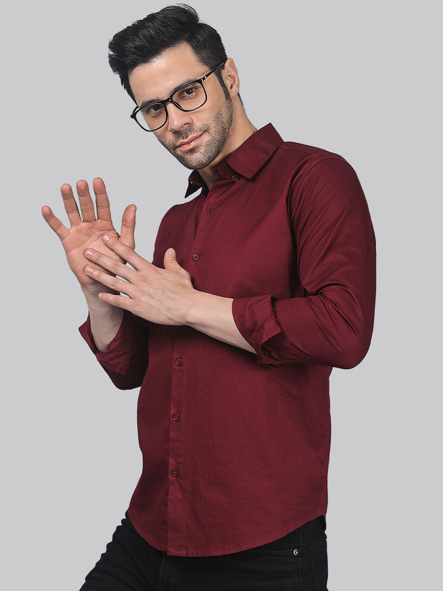 a man in a red shirt and black pants holding his hands together