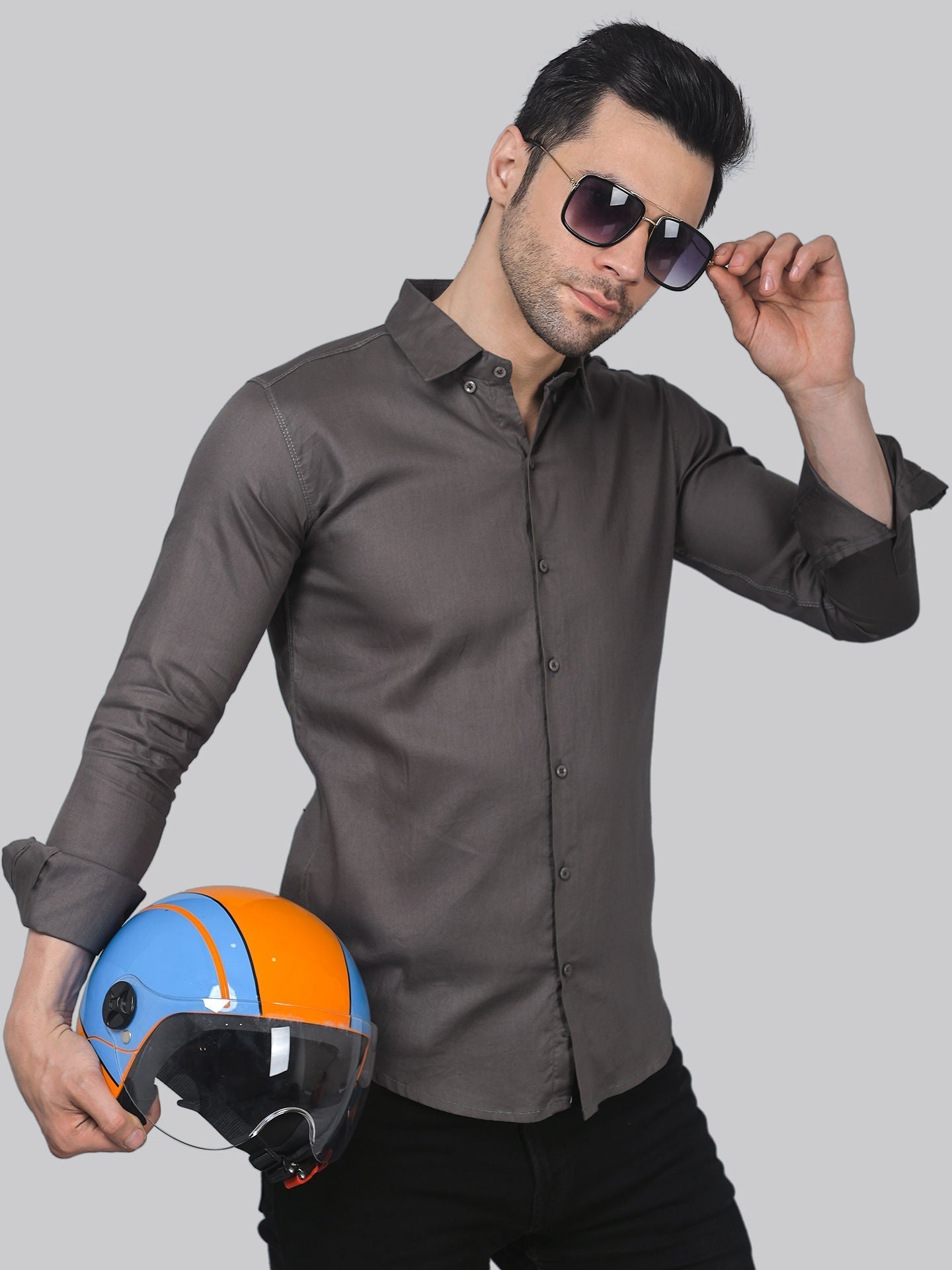 a man in a gray shirt and sunglasses holding a helmet