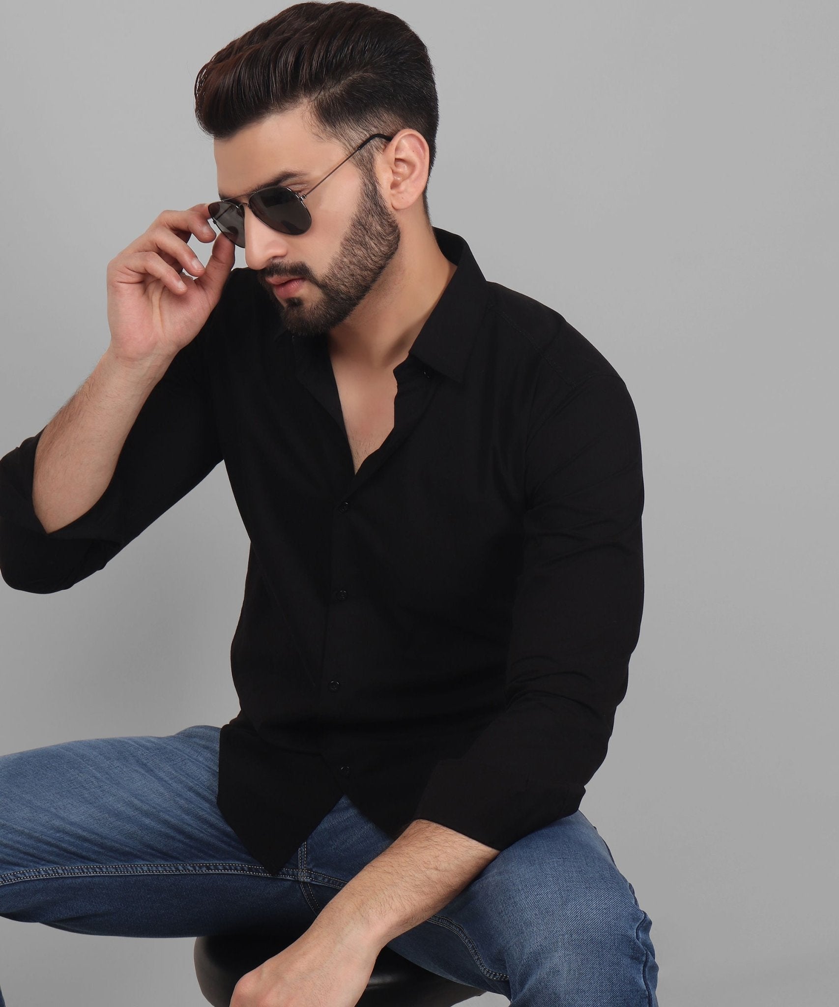 a man sitting on a stool talking on a cell phone